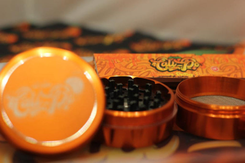 Orange herb grinder with a box in the background